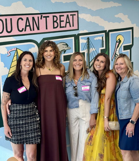 Five women wearing name badges in front of the You Can&rsquo;t Beat St. Pete mural.
